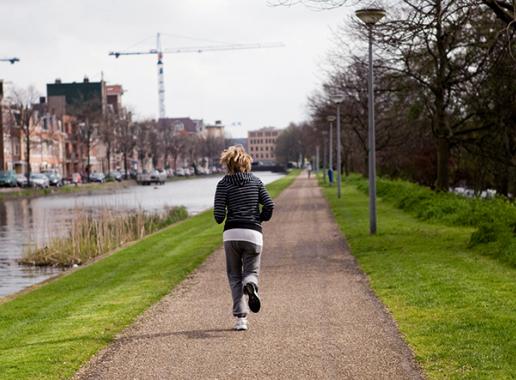 Goggen langs kanaal Vrouw jogt over wandelpad langs water