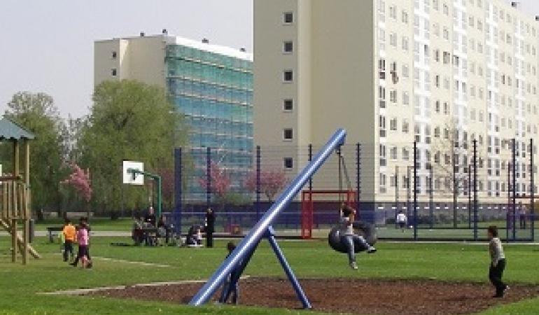 Flat met op de voorgrond speeltuin met spelende kinderen