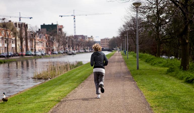 Goggen langs kanaal Vrouw jogt over wandelpad langs water