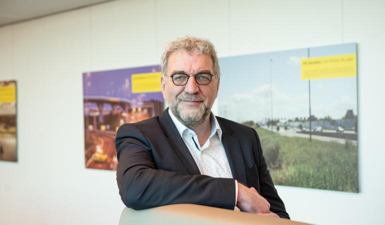 Ruud Splitthoff Portretfoto van de heer Ruud Splitthoff aan een hoge tafel met witte achtergrond waar posters hangen