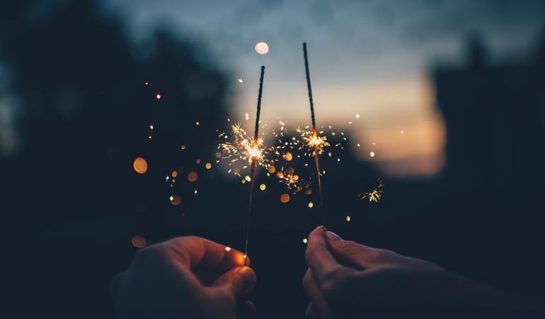 Vuurwerk sterretjes Twee mensen houden vuurwerk sterretjes omhoog tegen een schemer lucht