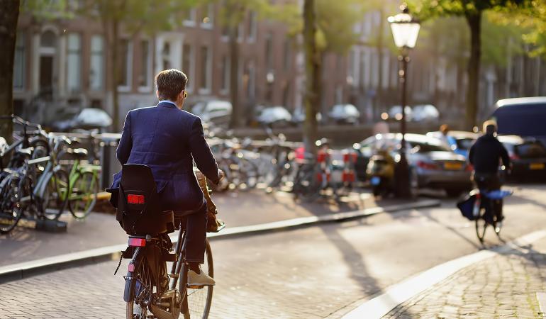 Man in pak fietst naar werk in binnenstad Amsterdam