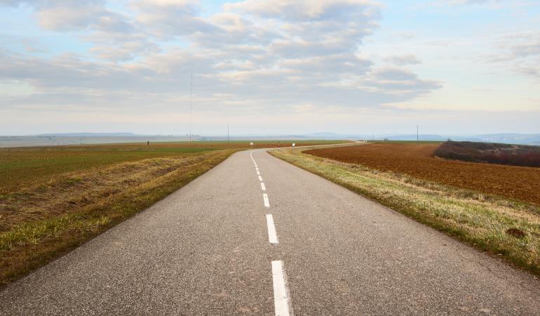 Weg in wijds landschap met hoge bewolking in de lucht