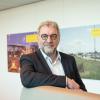 Ruud Splitthoff Portretfoto van de heer Ruud Splitthoff aan een hoge tafel met witte achtergrond waar posters hangen